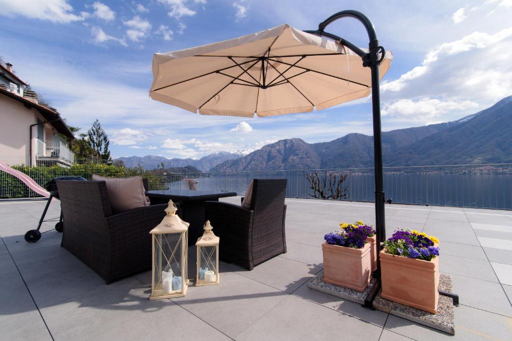 a patio with an umbrella and a table with flowers at Al Pontile - The House Of Travelers in Sala Comacina