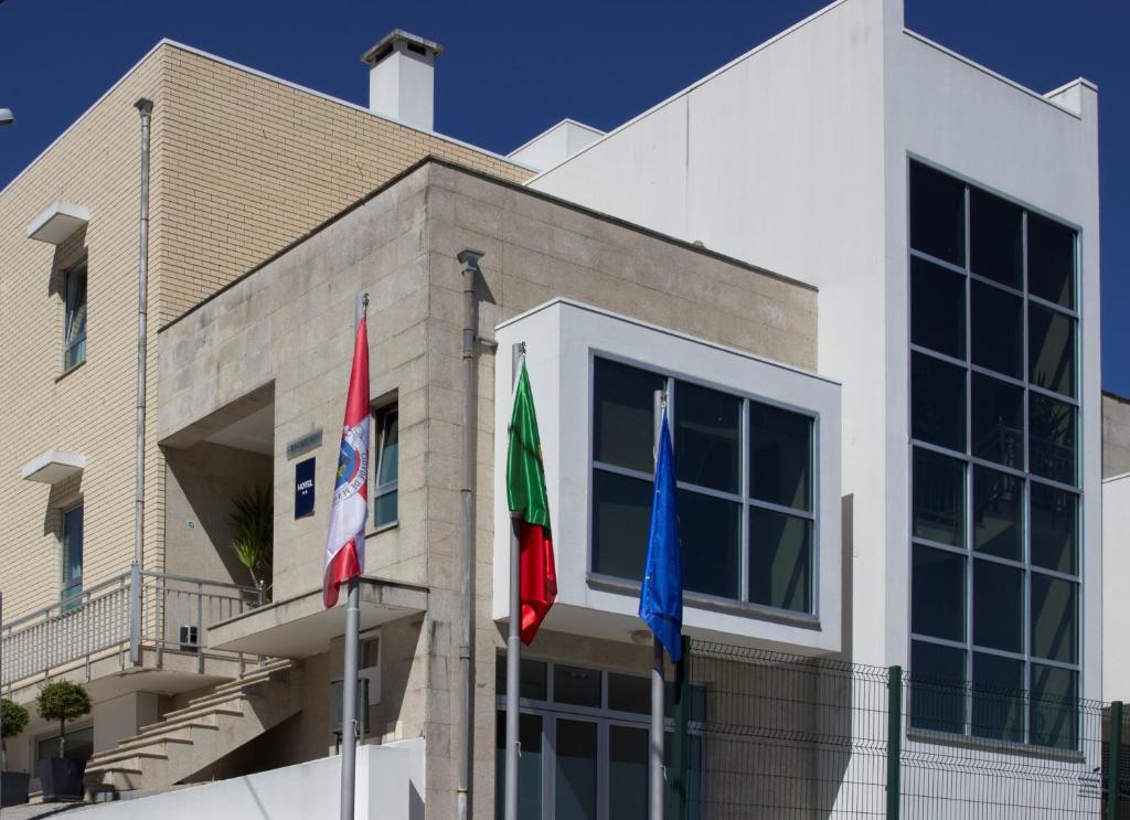 tres banderas delante de un edificio en Dom Hotel, en Penafiel