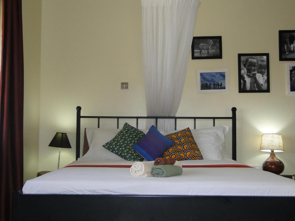1 dormitorio con 1 cama grande y almohadas coloridas en Carpe Diem Guesthouse, en Entebbe