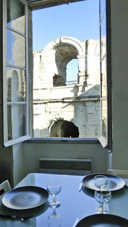 - une table avec une fenêtre et 2 verres à vin dans l'établissement Duplex meublé face aux arènes d'ARLES, à Arles