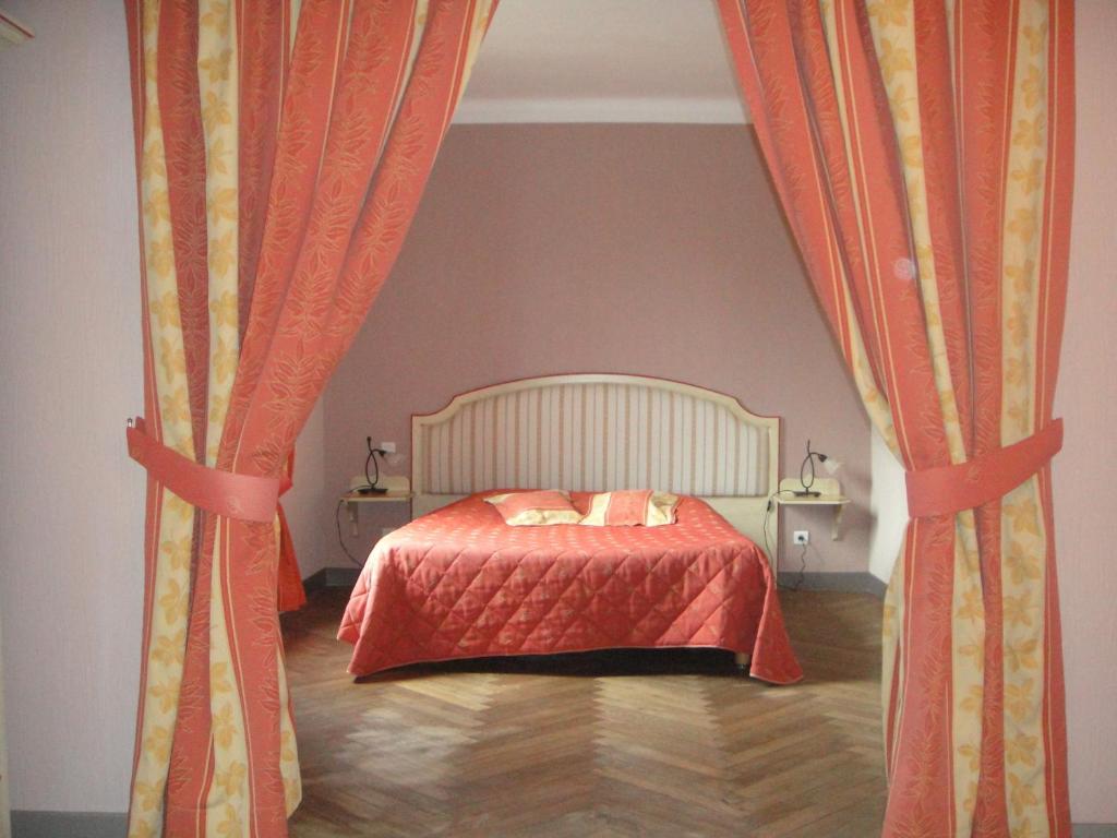 sypialnia z łóżkiem z pomarańczowymi zasłonami w obiekcie Auberge des Lices w Carcassonne