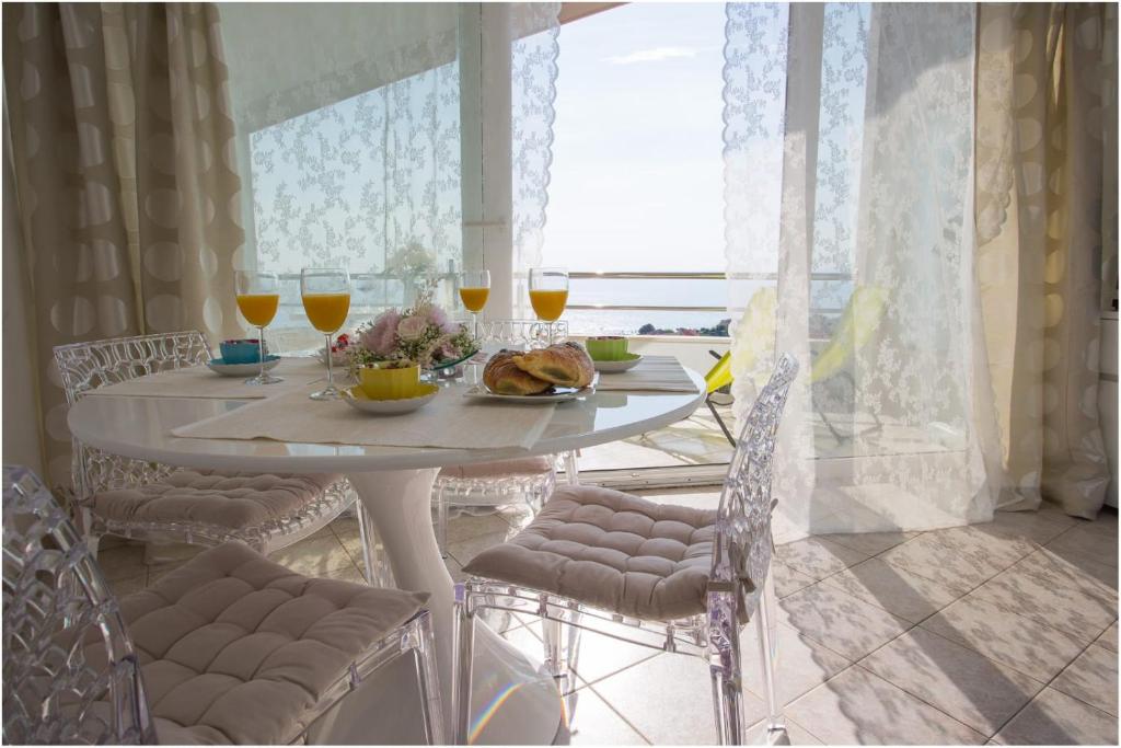 una mesa blanca con copas de vino y comida. en Apartments Maja, en Podstrana