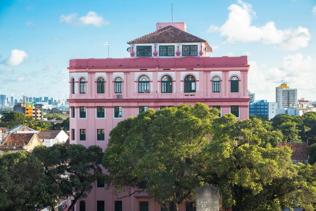 a pink building with a clock tower on top of it at Hotel Central in Recife