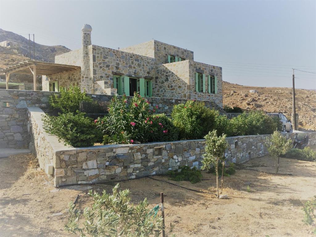 a house with a stone wall and some plants at Serifos Vacation Home in Rámos
