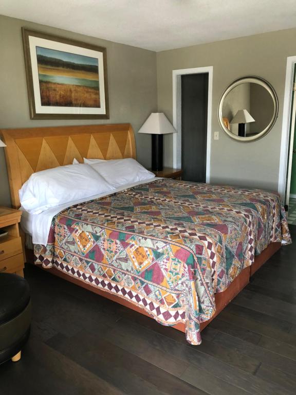 1 dormitorio con 1 cama grande y colcha colorida en Avon Motel, en Avon