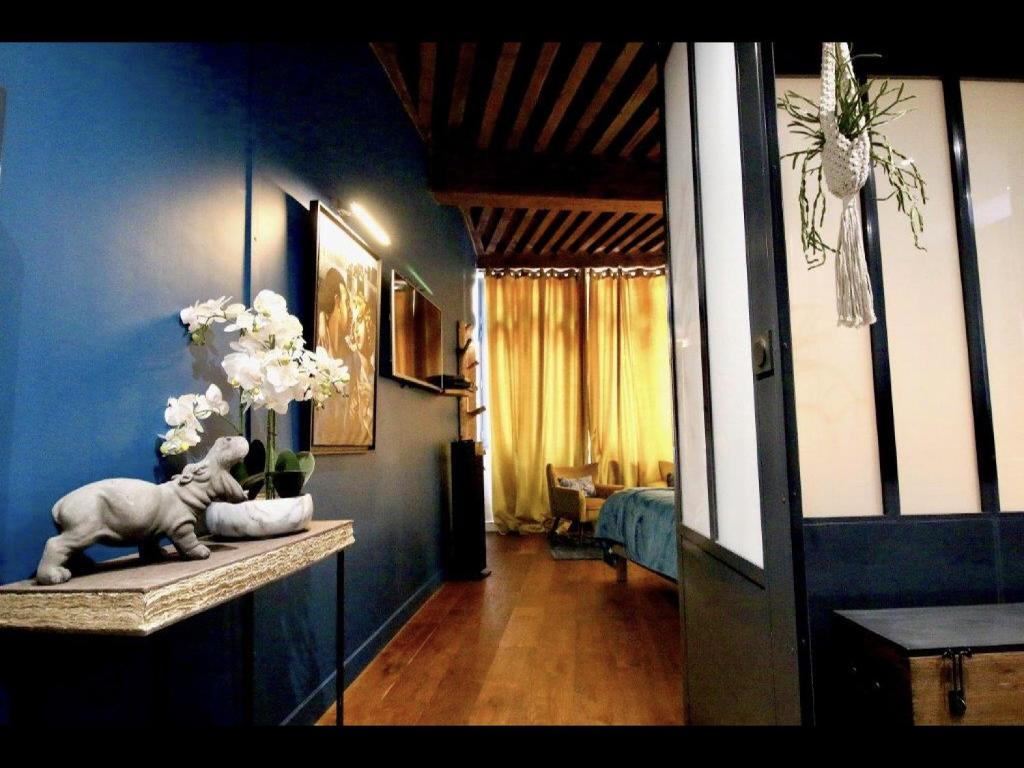 リヨンにある3e secret en plein coeur du Vieux Lyonの青い壁の客室で、花瓶を飾ったテーブルが備わります。