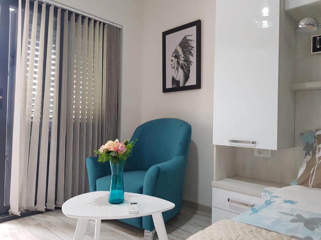 een slaapkamer met een blauwe stoel en een tafel met een vaas met bloemen bij Boka Bay Pearl in Kotor