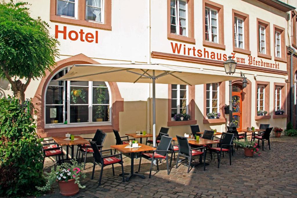 ein Hotel mit Tischen und Stühlen unter einem Sonnenschirm in der Unterkunft Wirtshaus zum Pferdemarkt in Saarburg
