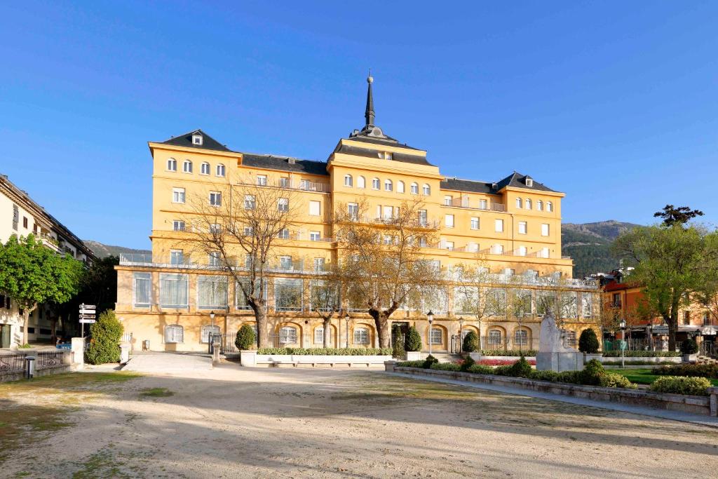 a large yellow building with a tower on top at Exe Victoria Palace in San Lorenzo de El Escorial