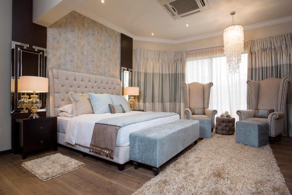 a bedroom with a large bed and two chairs at Villa Monticello Boutique Hotel in Accra