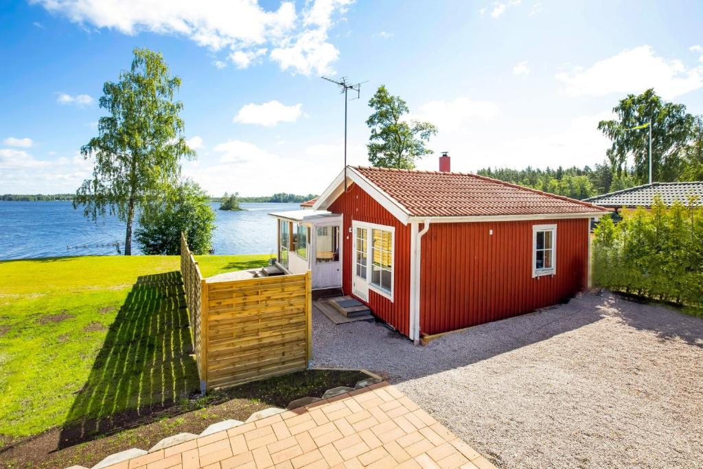 um barracão vermelho com uma cerca ao lado de uma massa de água em Holiday Lakefront house em Björköby