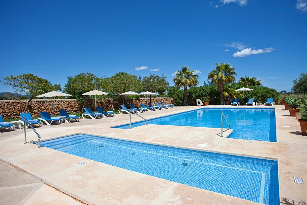 a large swimming pool with chairs and umbrellas at Agroturisme Na Martina in Portopetro