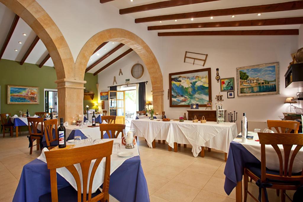 a restaurant with white tables and chairs with blue table cloth at Agroturisme Na Martina in Portopetro