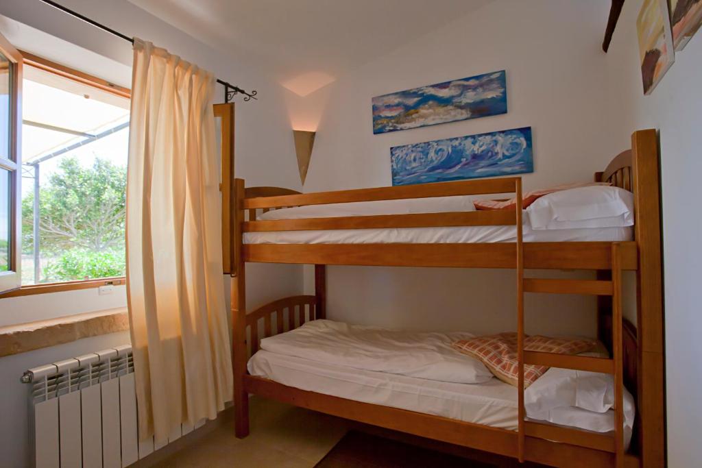 a room with three bunk beds and a window at Agroturisme Na Martina in Portopetro