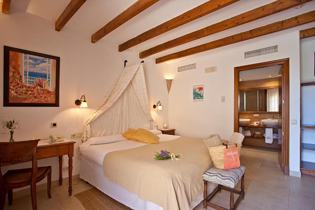 a bedroom with a bed and a desk and a table at Agroturisme Na Martina in Portopetro