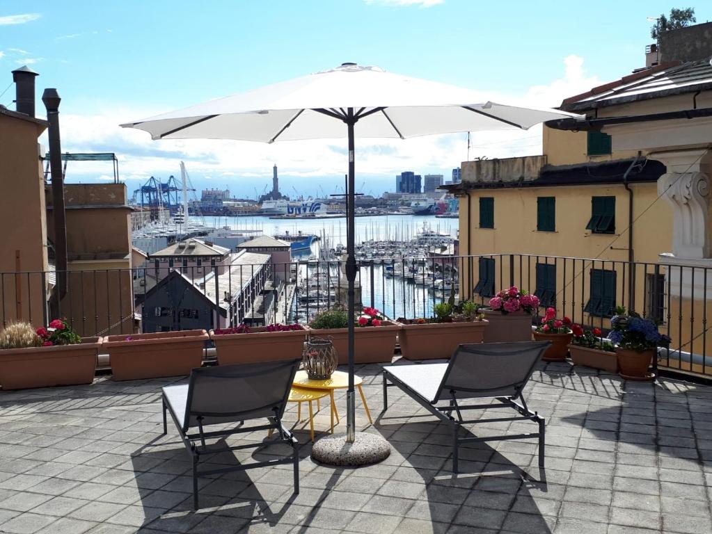 um pátio com 2 cadeiras, uma mesa e um guarda-sol em Old Genoa Rooms & Apartments em Gênova