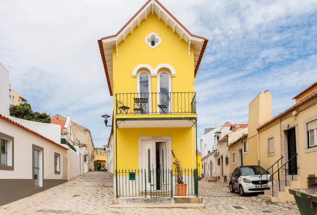 a yellow house with a balcony on a street at Lisbon Sea Side Chalet in Paço de Arcos