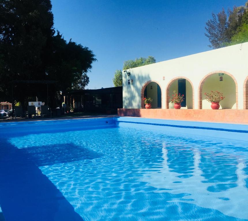 una piscina de agua azul frente a un edificio en Hotel RV Park San Ramón, en San Miguel de Allende