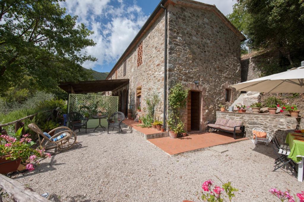 ein Steingebäude mit einer Terrasse und einem Sonnenschirm in der Unterkunft Fienile Vignanova in Gerfalco