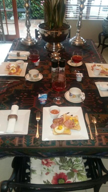 a table with plates of food and glasses of wine at Bella's B&B in Vryheid