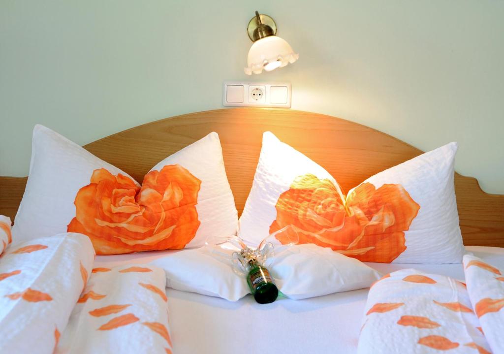 un letto con cuscini arancioni e una bottiglia sopra di Frühstückspension Rüf ad Au im Bregenzerwald
