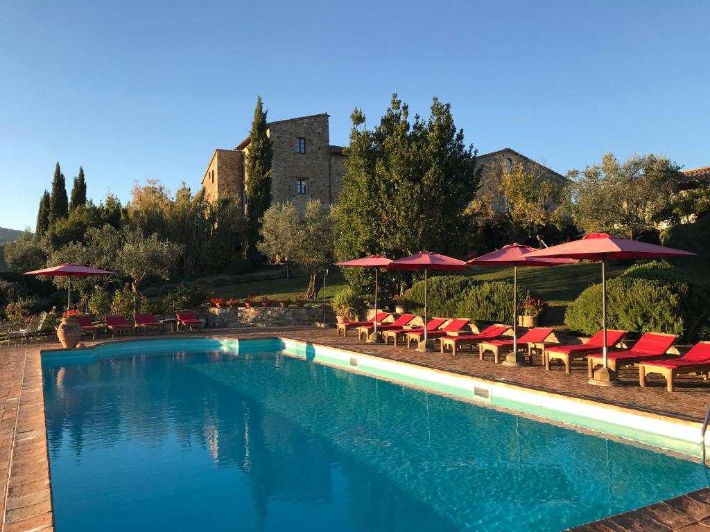 einen Pool mit roten Stühlen und Sonnenschirmen in der Unterkunft Tenuta Di Canonica in Todi