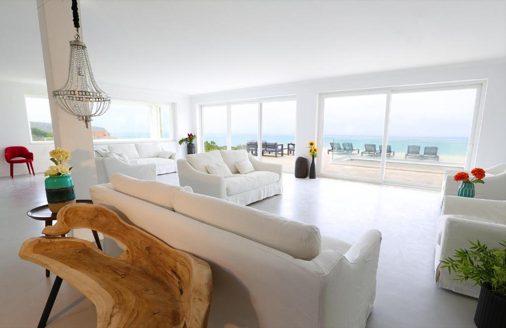シントラにあるPG - Beach Houseの白い家具付きのリビングルームが備わり、海の景色を望めます。