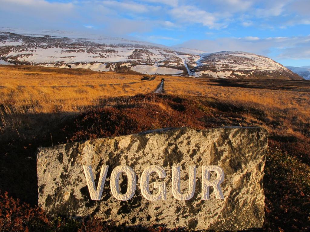 Vogur Country Lodge في Vogur: لافته مكتوب فيها سم على ارض فيها جبال مغطاة بالثلج