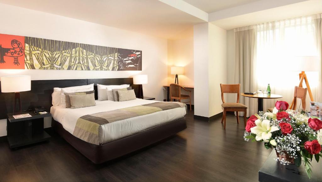 pokój hotelowy z łóżkiem i stołem z kwiatami w obiekcie Hotel Eurotel Providencia w mieście Santiago