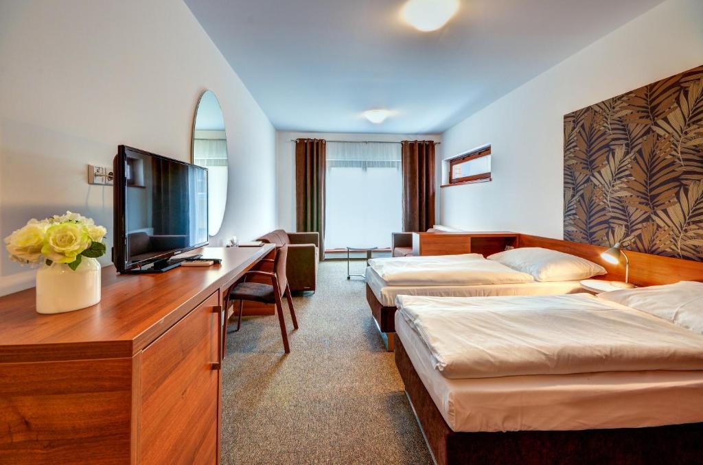 ein Hotelzimmer mit 3 Betten und einem TV in der Unterkunft Hotel Iberia in Opava