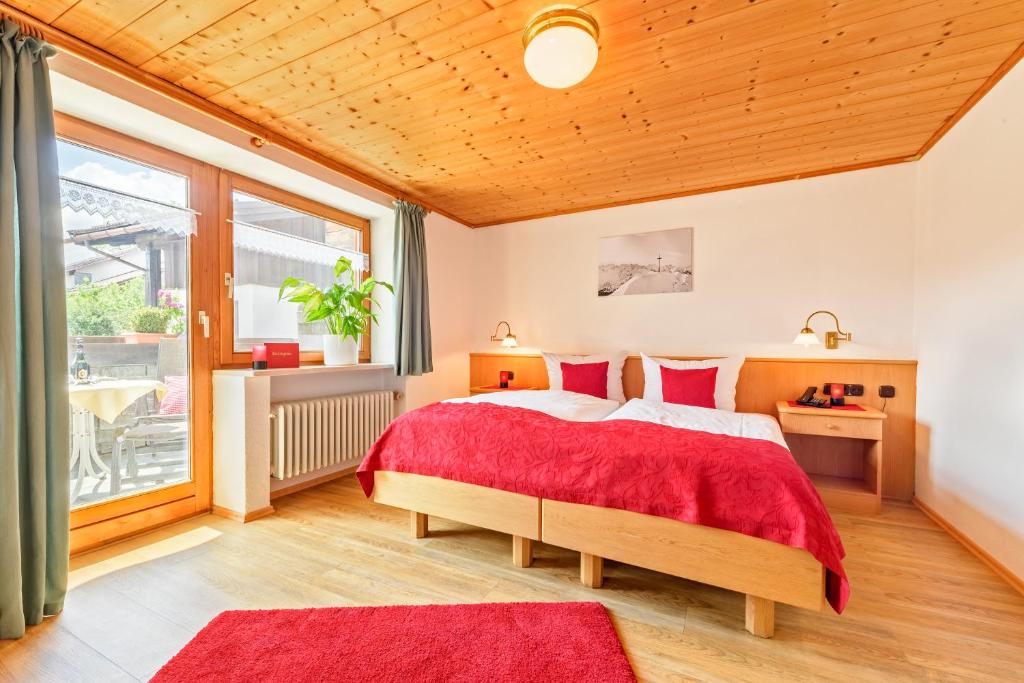 a bedroom with a large bed with red pillows at Familien- und Wellnesshotel "Landhaus Viktoria" in Oberstdorf
