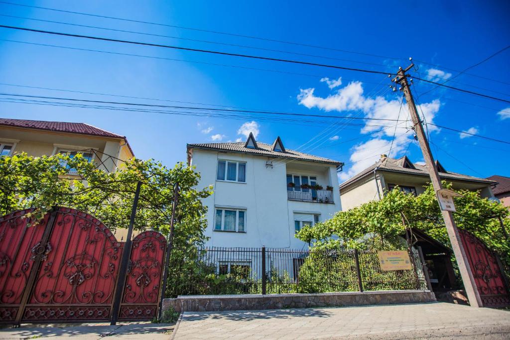 un edificio blanco con una puerta roja y una valla en Guest House in Drachino, en Svalyava