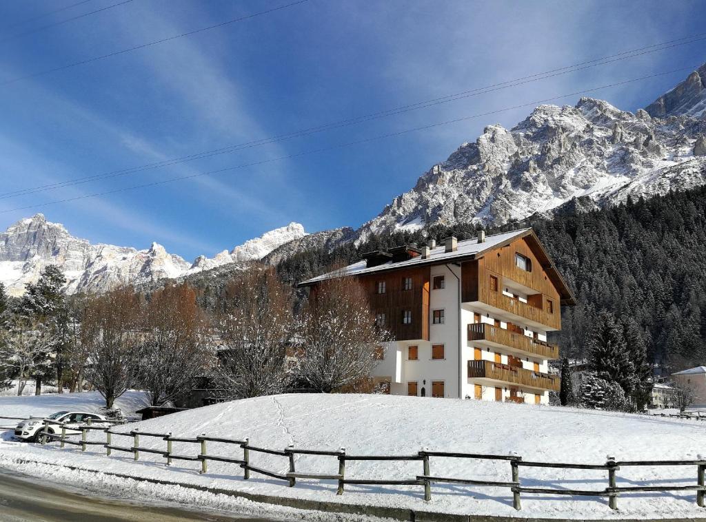 a building in the snow with mountains in the background at Botton d'oro in Borca di Cadore