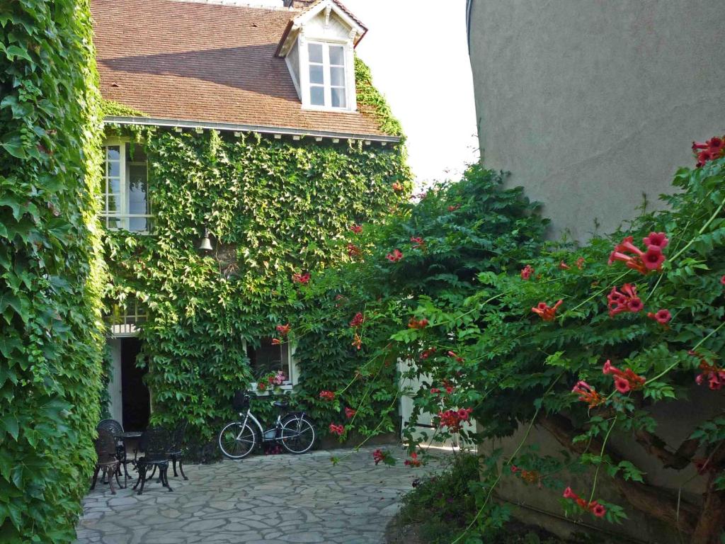 una casa cubierta de hiedra con una bicicleta estacionada fuera en La Vigne Vierge, en Châteauneuf-sur-Loire