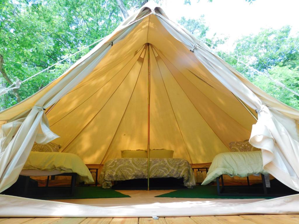ein großes gelbes Zelt mit drei Betten in der Unterkunft Glampin' In Style-Broken Bow in Broken Bow