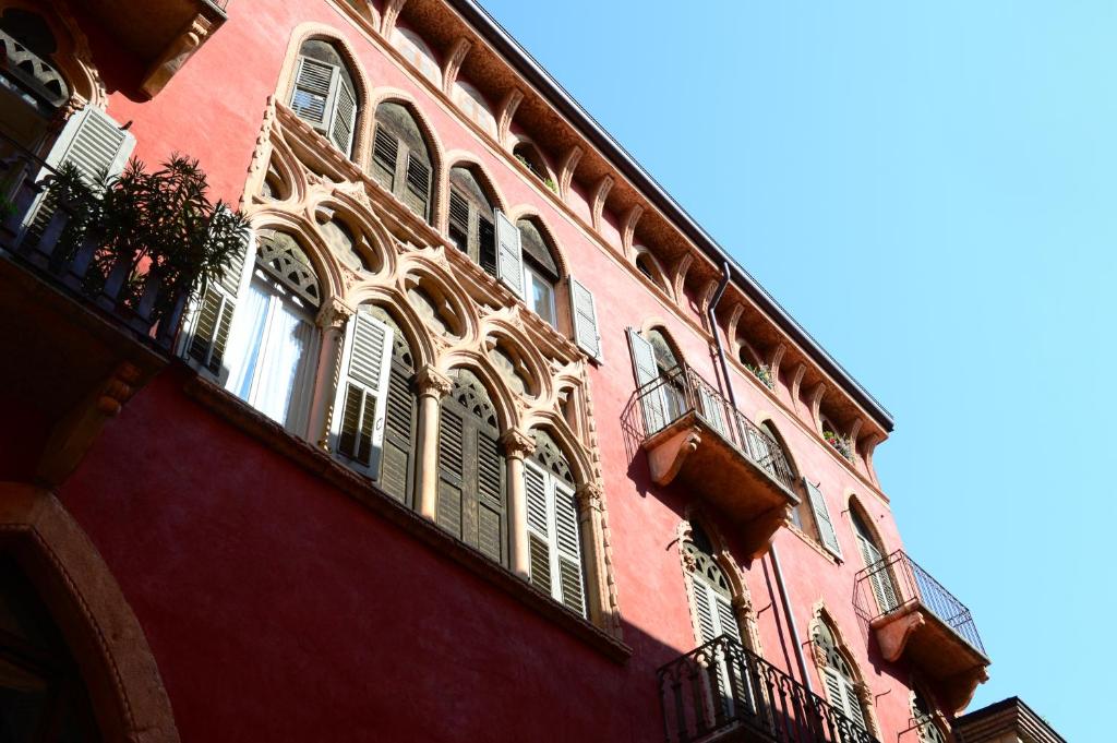 - un bâtiment rouge avec des fenêtres et des balcons dans l'établissement Suite della Scala, à Vérone