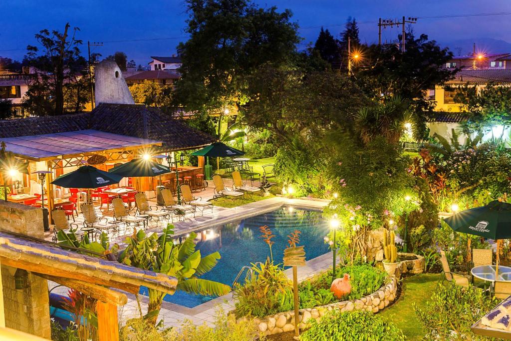 a resort with a pool and tables and umbrellas at night at Hotel Rincon de Puembo; BW Signature Collection in Puembo