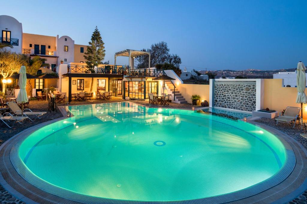 a large swimming pool in front of a house at Kalimera Hotel in Akrotiri