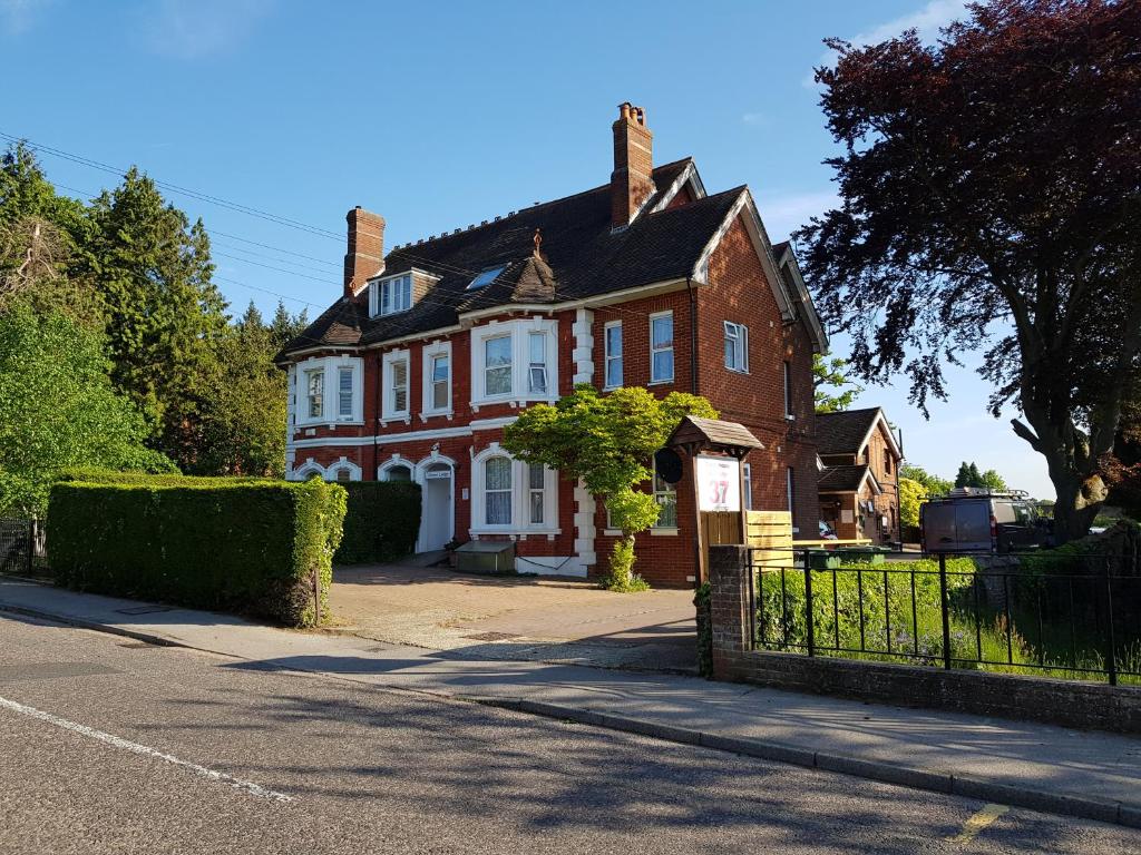 a large red brick house with a black fence at Anand Lodge in Royal Tunbridge Wells