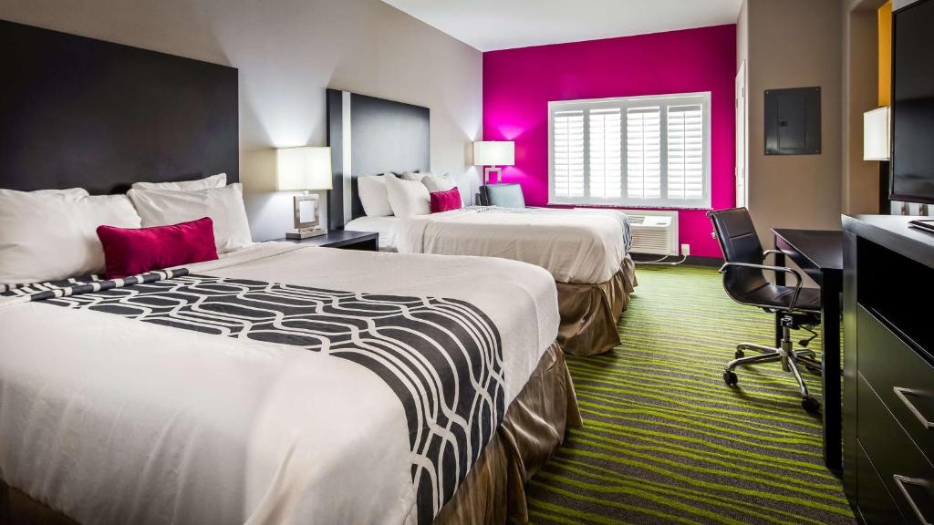 a hotel room with two beds and pink walls at Best Western Plus Dilley Inn & Suites in Dilley