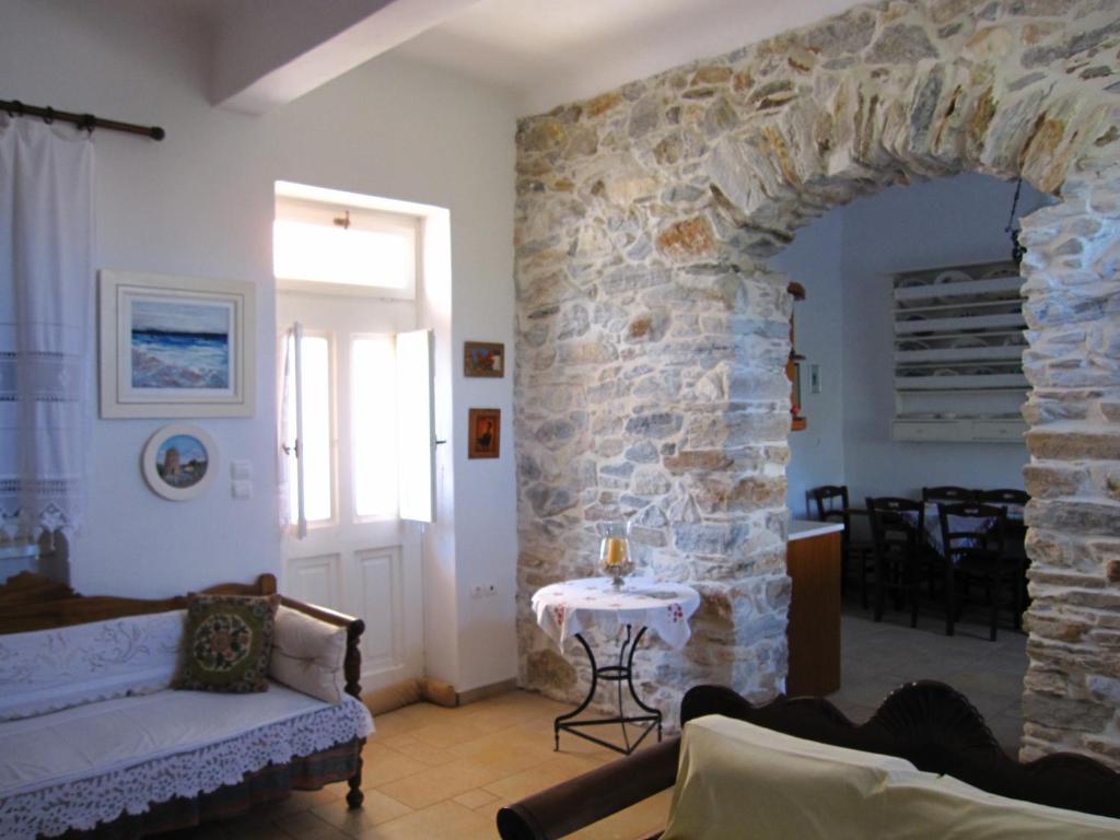 Luxury 100 m2 house in the centre of Naxos في Dhamariónas: غرفة معيشة مع جدار حجري وأريكة