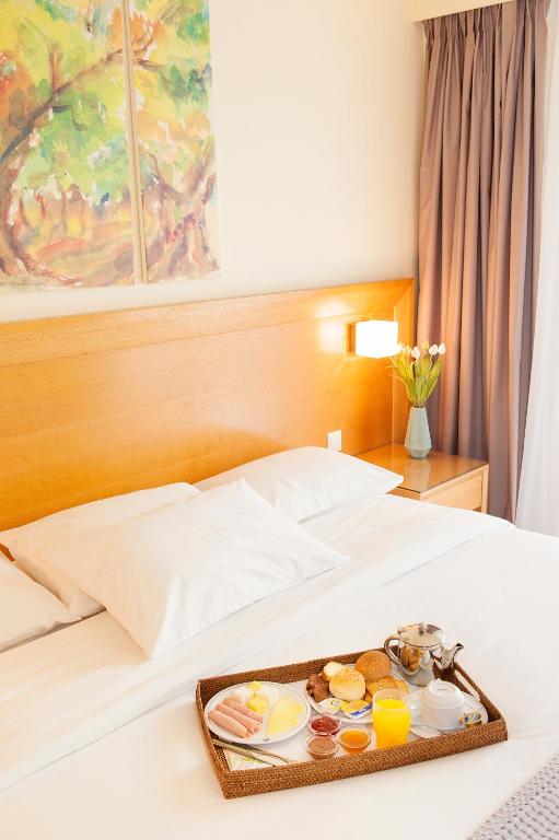 a tray with breakfast foods on a bed at Athinais Hotel in Athens
