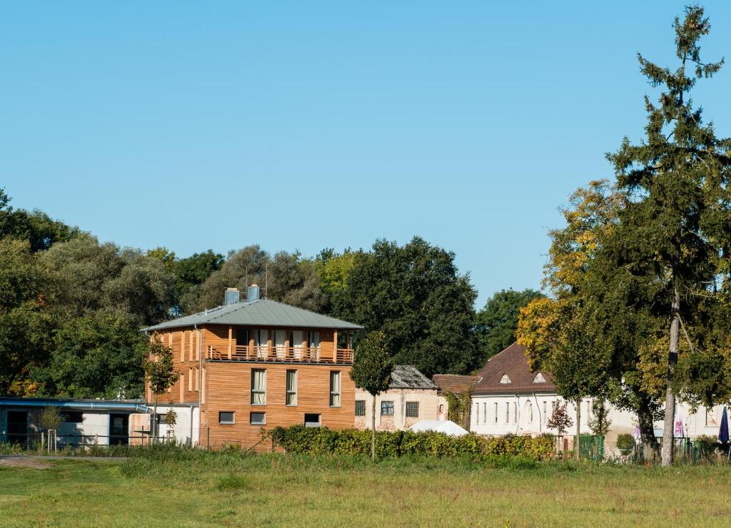 a large brick building in a field with trees at Gästehaus am Landgut in Schönwalde