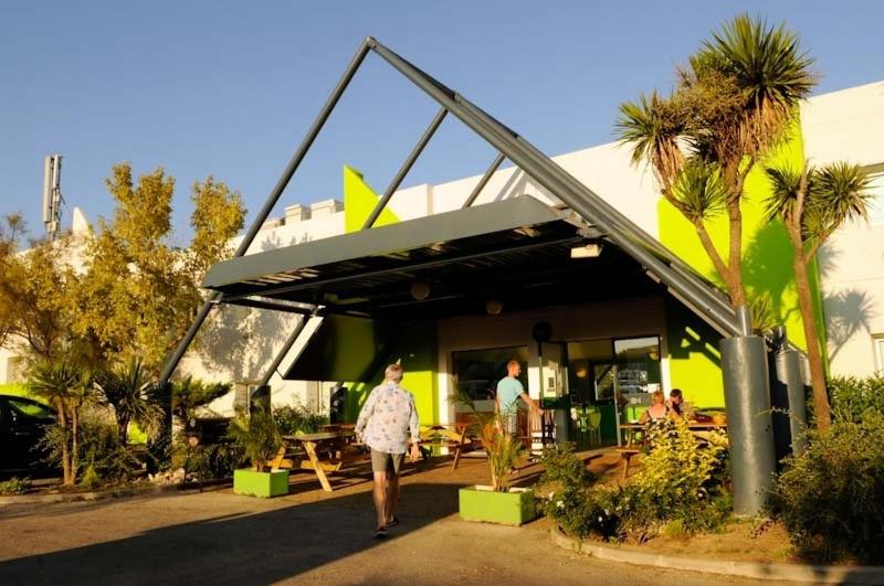 a person walking past a restaurant with awning at Lemon Hotel Plan de Campagne Marseille in Septèmes-les-Vallons