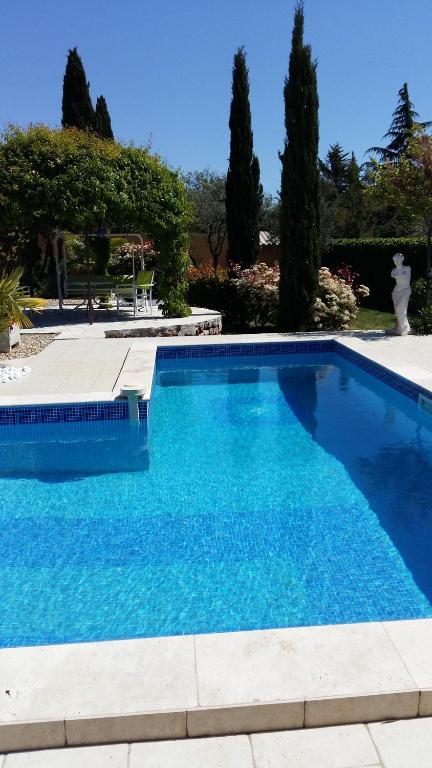 una gran piscina azul con árboles en el fondo en Villa Azurella, en Brignoles