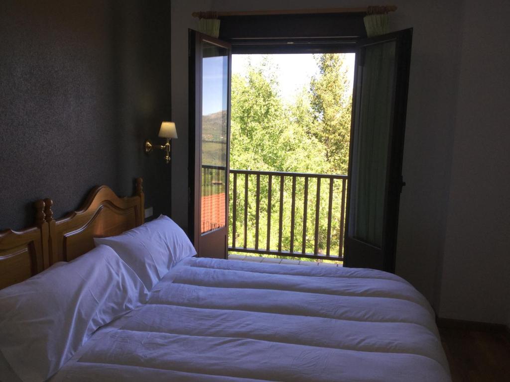 a bedroom with a bed and a large window at Hotel Cinco Castaños in Candelario