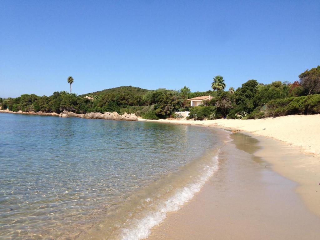 a sandy beach with water and trees in the background at Villa Ghiatone in Pietrosella