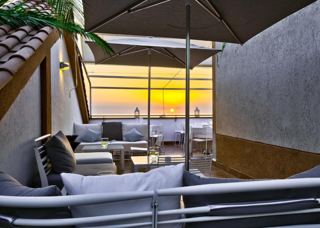 パリヌーロにあるHotel San Paoloのカウチとテーブル、傘が備わるレストラン