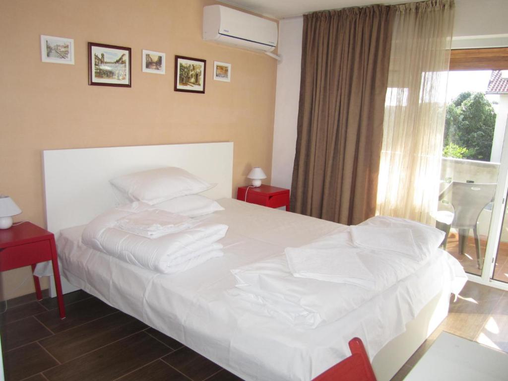 Un dormitorio con una gran cama blanca y una ventana en Guesthouse Kolevi, en Lozenets