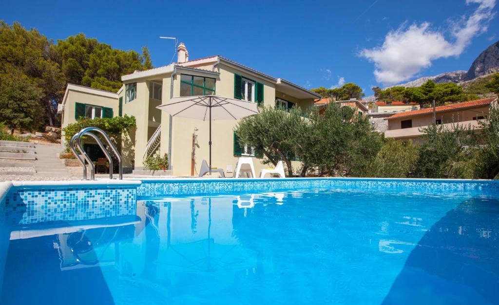 ein Haus mit einem Pool vor einem Haus in der Unterkunft Villa Stina in Baška Voda